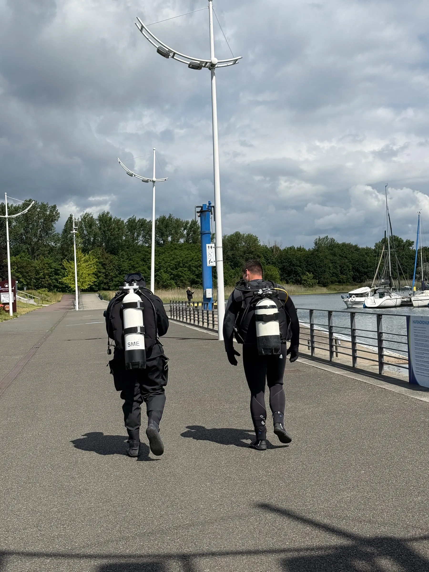Zwei Taucher mit Flasche auf dem Weg von der Basis zum Wasser